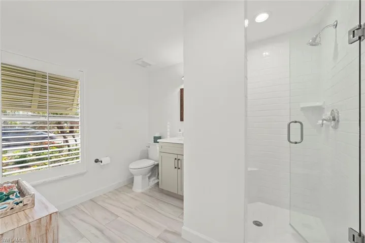 Bathroom featuring toilet, visible vents, vanity, baseboards, and a stall shower