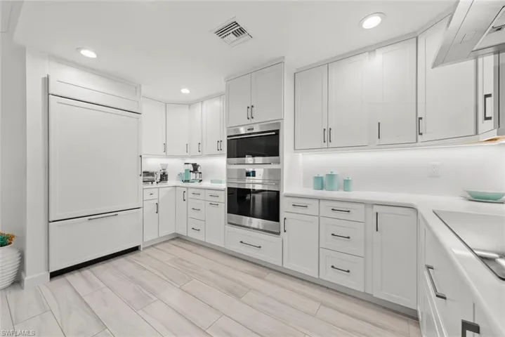 Kitchen with visible vents, white cabinets, paneled built in refrigerator, light countertops, and double oven