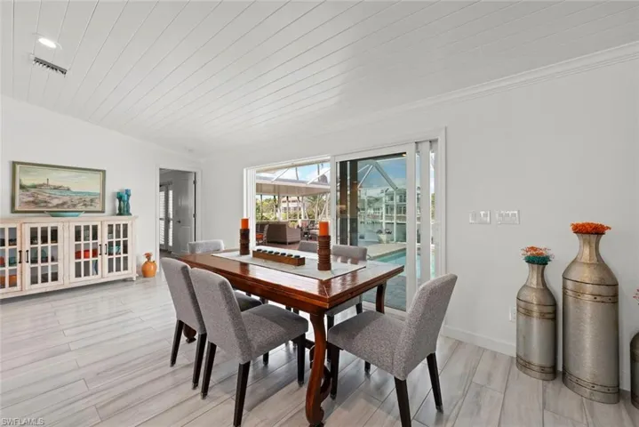 Dining room with baseboards, a sunroom, wooden ceiling, crown molding, and light wood-type flooring