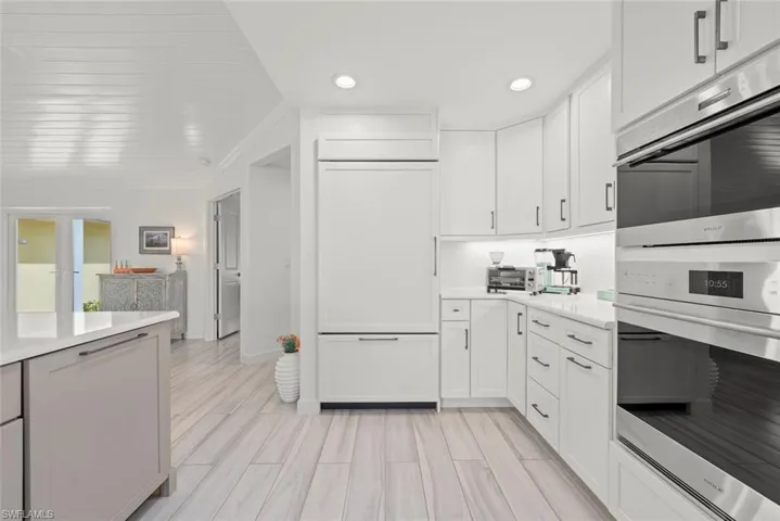 Kitchen featuring wood finish floors, light countertops, paneled fridge, and white cabinetry