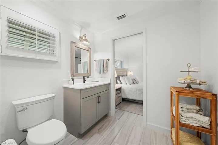 Ensuite bathroom featuring toilet, vanity, visible vents, ensuite bath, and crown molding