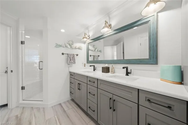 Bathroom with a sink, a shower stall, baseboards, and double vanity