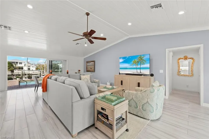 Living room with lofted ceiling, baseboards, visible vents, and recessed lighting