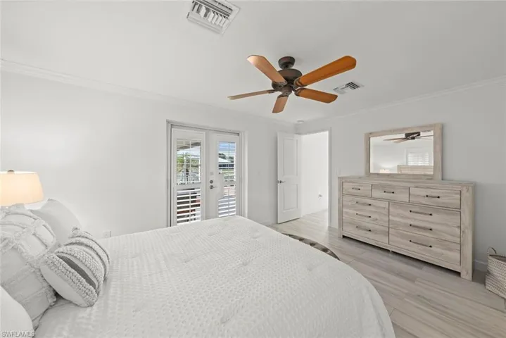 Bedroom with access to exterior, light wood-style floors, visible vents, and crown molding
