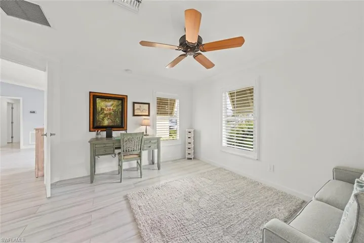 Office area featuring baseboards, wood finished floors, visible vents, and crown molding