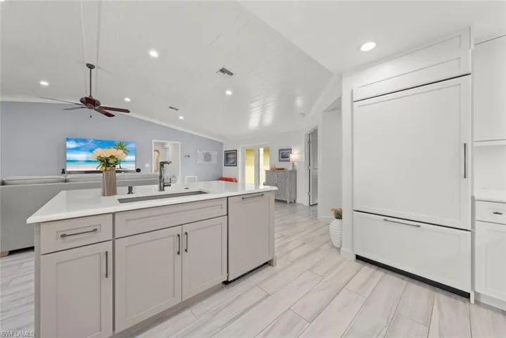 Kitchen featuring paneled dishwasher, open floor plan, a sink, and light countertops