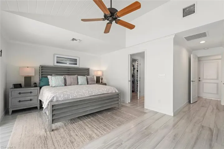 Bedroom featuring light wood-style flooring, visible vents, and crown molding