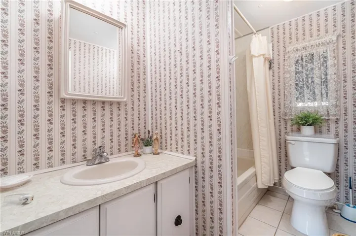 Full bathroom featuring toilet, tile patterned flooring, shower / bath combo with shower curtain, and vanity