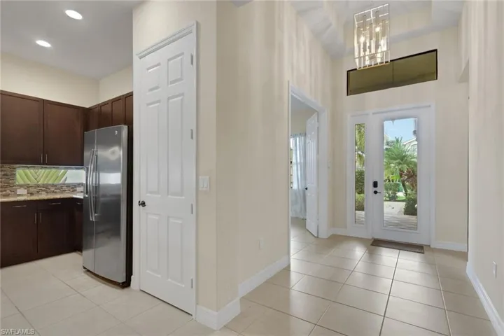Entry foyer with coffered ceiling, upgraded lighting and doors leading to the den to the right upon entry