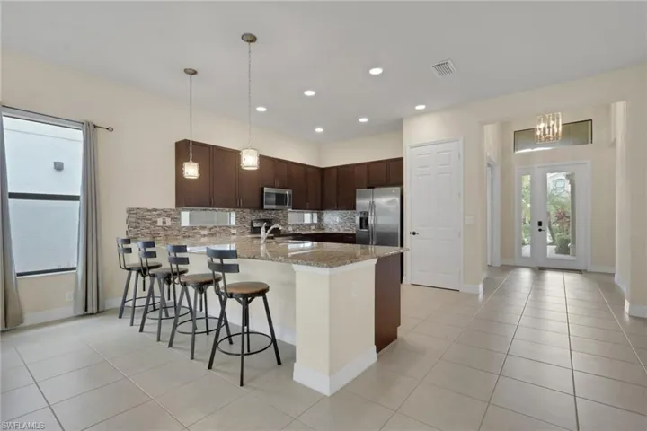 Kiitchen with transom glass lighting, top hats, granite countertop and pantry; formal dining area to the left