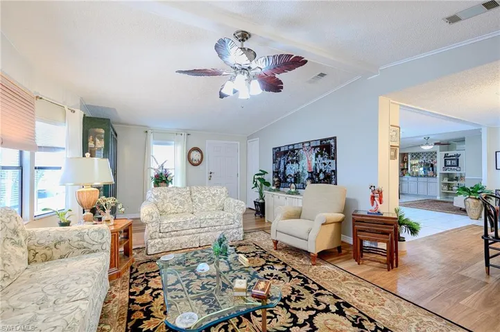 Living area with ceiling fan, wood finished floors, a textured ceiling, baseboards, and crown molding