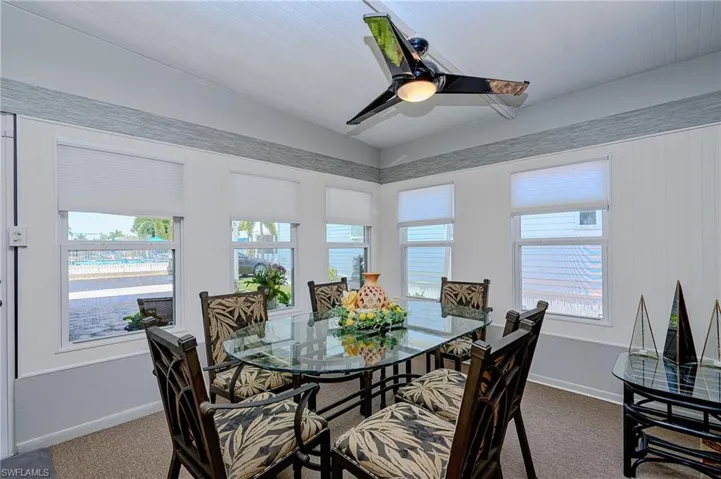 Dining room featuring dark colored carpet, plenty of natural light, a ceiling fan, baseboards, and lofted ceiling