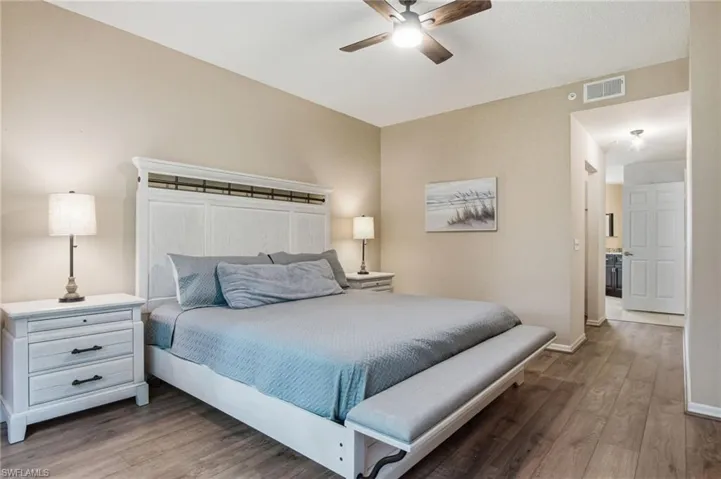 Spacious bedroom featuring wood-finish flooring, a ceiling fan with integrated lighting, and neutral wall tones