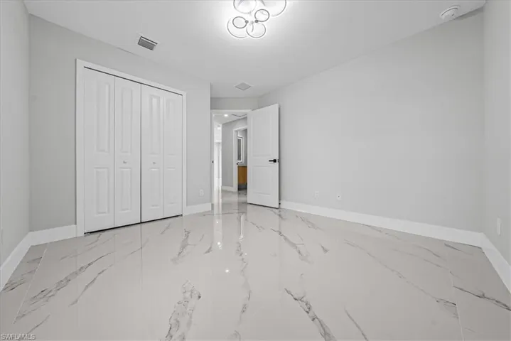 Spacious room featuring large format tile flooring, a contemporary ceiling light fixture, and bifold closet doors