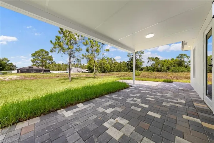Covered patio with patterned paver flooring and an outdoor light fixture