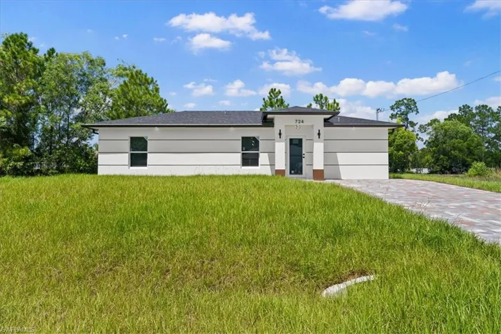 Contemporary architectural style featuring a dark shingle roof, white exterior with gray banding, and a paver driveway