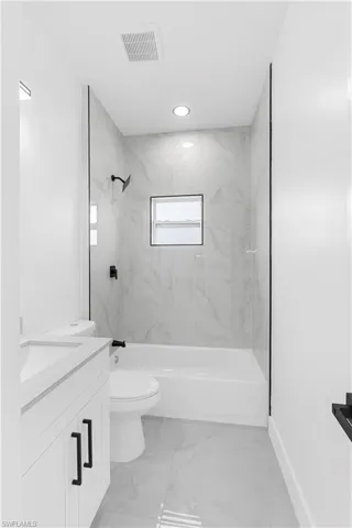 Full bathroom featuring vanity, light marble finish floors, a combined bath / shower with marble appearance, and recessed lighting