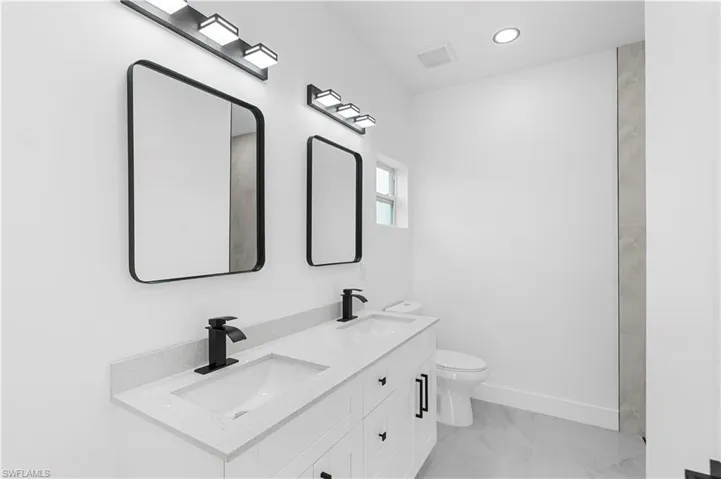 Full bath featuring light marble finish flooring, double vanity, and recessed lighting