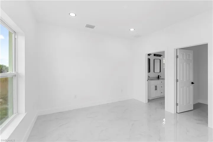 Unfurnished bedroom featuring light marble finish floors, connected bathroom, and recessed lighting