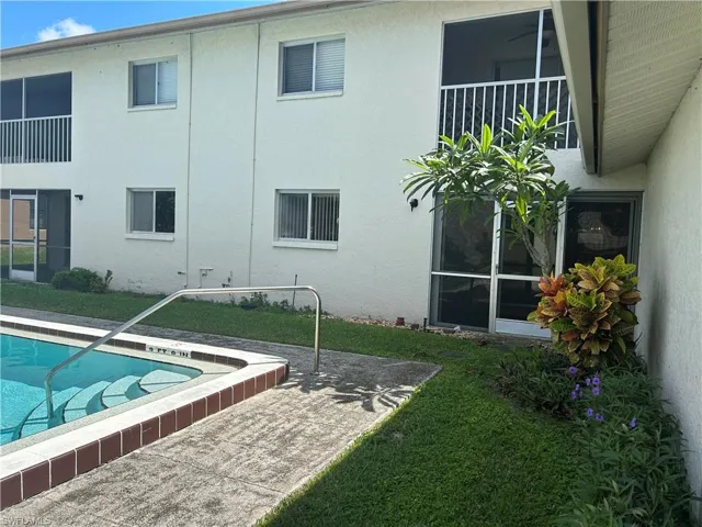 Rear view of property with an outdoor pool, stucco siding, and a yard