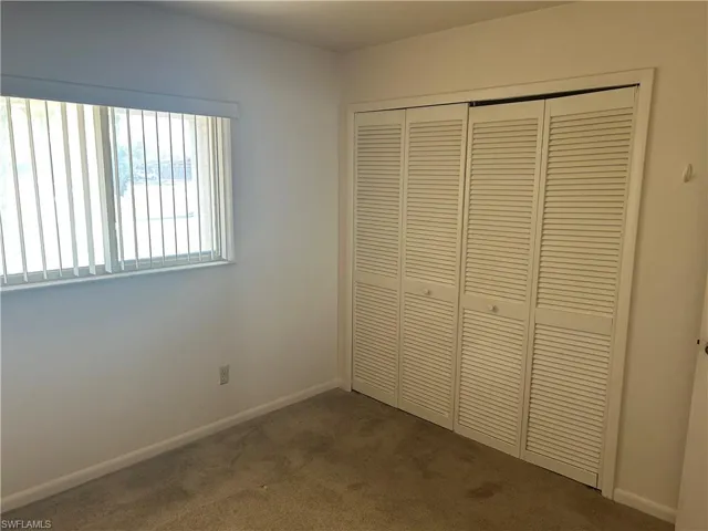 Unfurnished bedroom featuring dark carpet and a closet