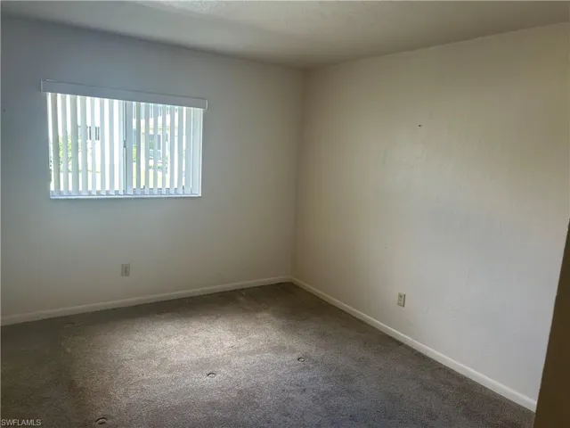 Carpeted spare room featuring baseboards