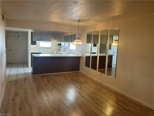 Kitchen featuring light countertops, a peninsula, white electric range, light wood-type flooring, and pendant lighting