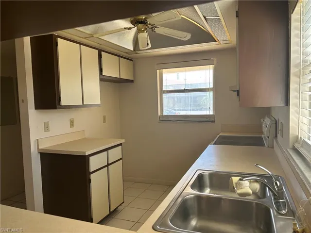 Kitchen with light tile patterned floors, electric range, white cabinetry, and ceiling fan