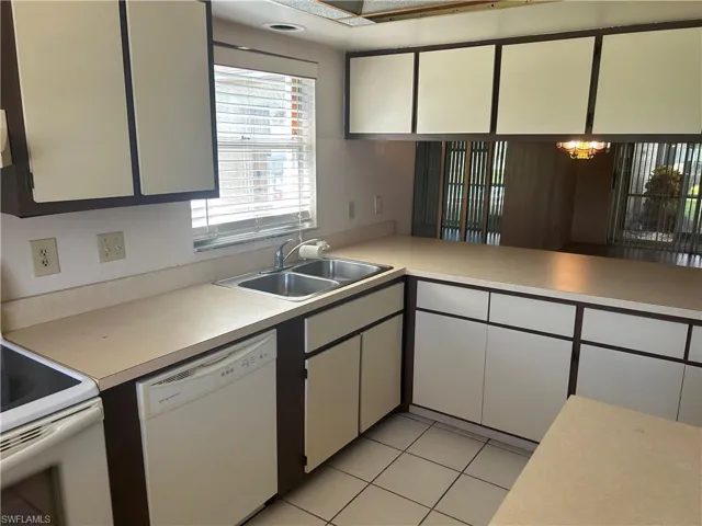 Kitchen with white appliances, light tile patterned floors, light countertops, white cabinets, and decorative light fixtures