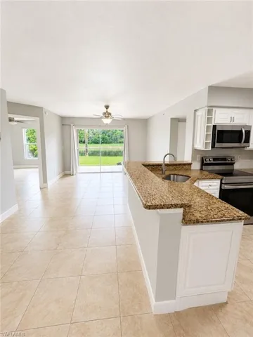 Kitchen features a granite-top breakfast bar with built-in sink and white paneled cabinetry