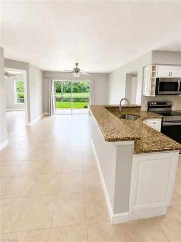 Kitchen island with granite countertop and integrated sink featuring a pull-down faucet