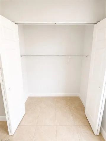 Closet space featuring bi-fold doors, neutral wall paint, a wire shelving system, and tiled flooring