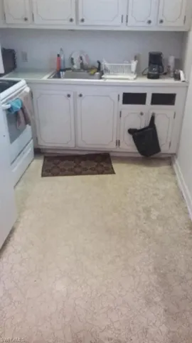 Kitchen with white electric range oven, light countertops, light flooring, and white cabinets