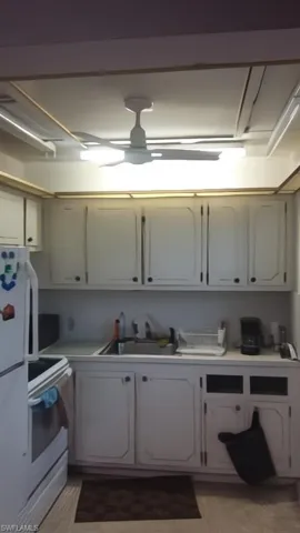 Kitchen with white range with electric stovetop, light countertops, and fridge