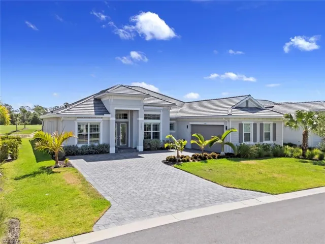 View of front of house with decorative driveway, stucco siding, a front yard, and a tile roof