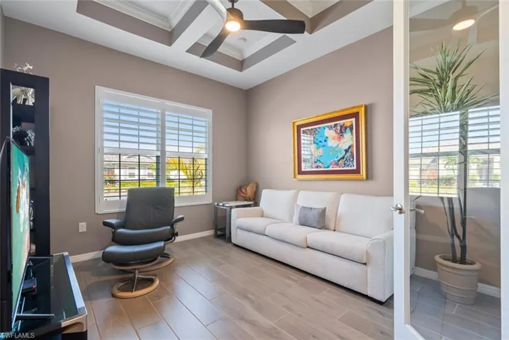 Living area with ornamental molding, wood finished floors, baseboards, ceiling fan, and coffered ceiling