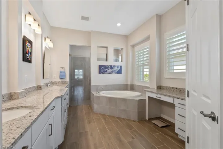 Full bath with a sink, visible vents, tiled shower, and a garden tub