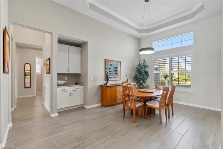 Dining room with crown molding, baseboards, and a raised ceiling