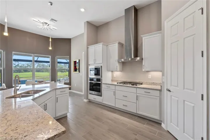 Kitchen featuring visible vents, a sink, a high ceiling, stainless steel appliances, and wall chimney exhaust hood