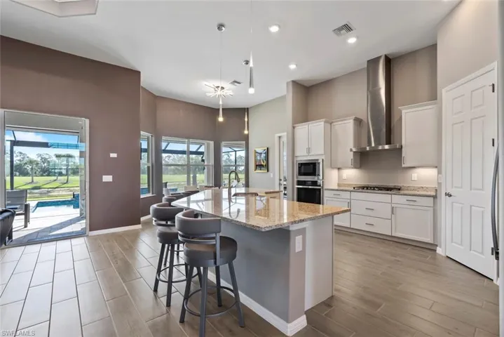 Kitchen featuring a sink, appliances with stainless steel finishes, wood tiled floor, and wall chimney exhaust hood