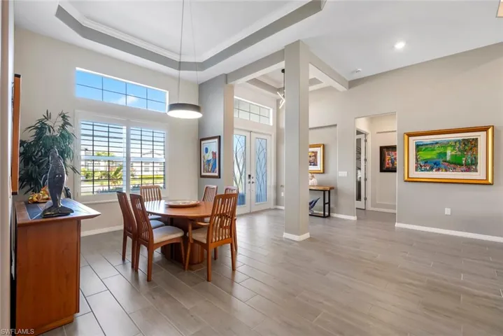 Dining room featuring crown molding, a raised ceiling, baseboards, and plenty of natural light