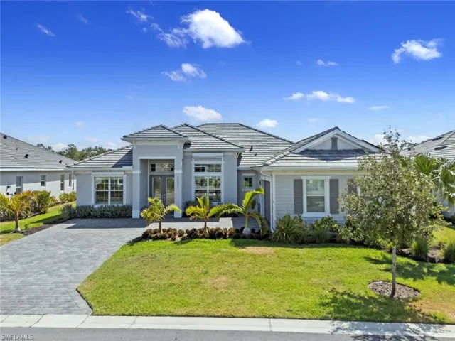 View of front of house with stucco siding, a tile roof, and a front lawn