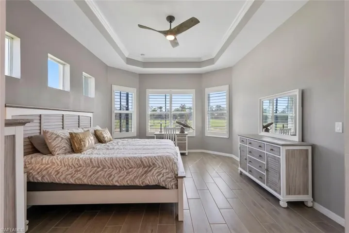 Bedroom featuring a raised ceiling, baseboards, and wood tiled floor