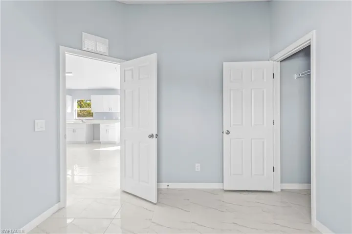 Unfurnished bedroom with a towering ceiling and light marble finish floors