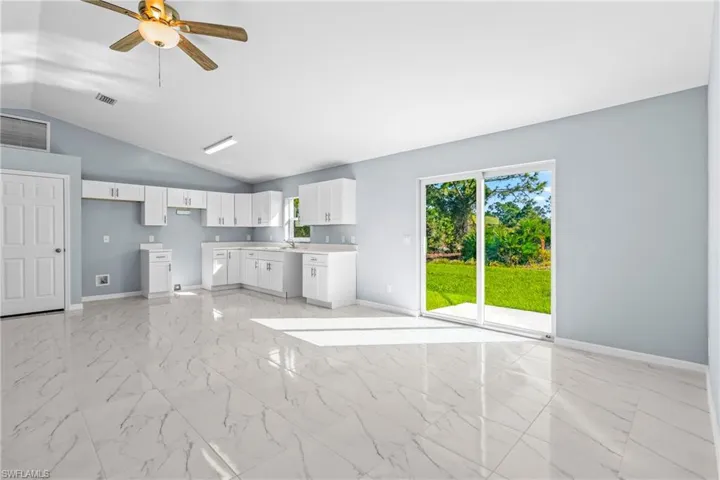 Unfurnished living room featuring light marble finish flooring, lofted ceiling, and ceiling fan