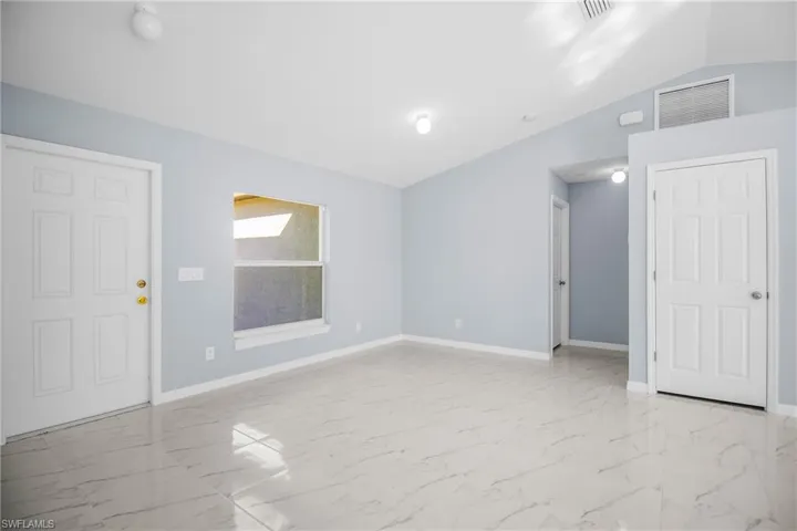 Unfurnished room featuring lofted ceiling and light marble finish flooring