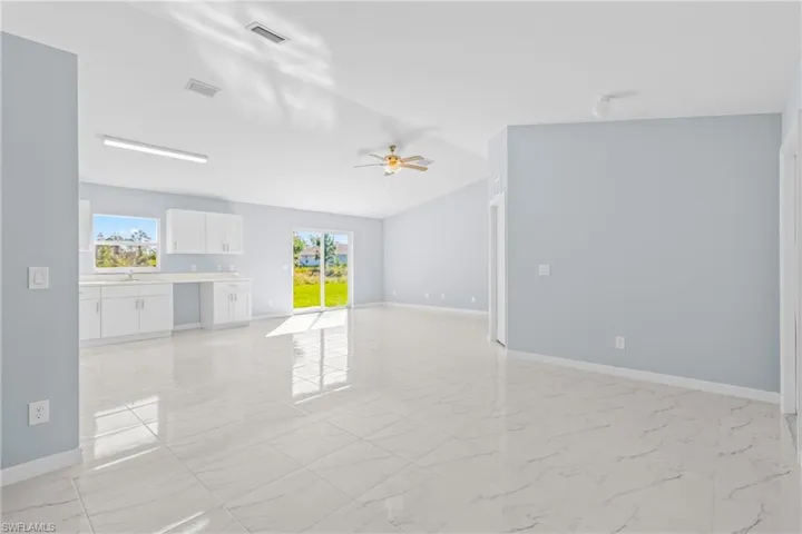Unfurnished living room with light marble finish floors and ceiling fan