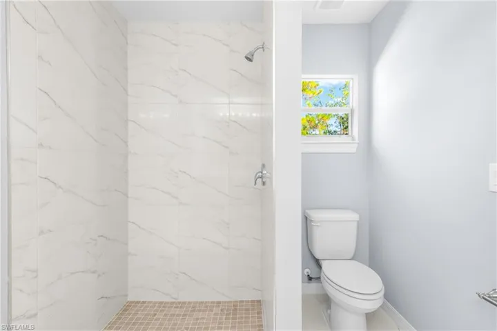 Full bathroom with a marble finish shower and tile patterned flooring
