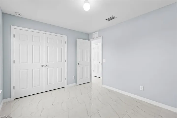 Unfurnished bedroom with light marble finish floors and a closet