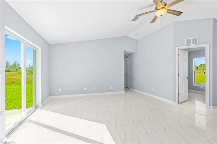 Spare room with light marble finish floors, ceiling fan, and vaulted ceiling